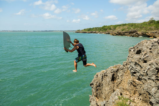 surfer jumps off a cliff into the ocean