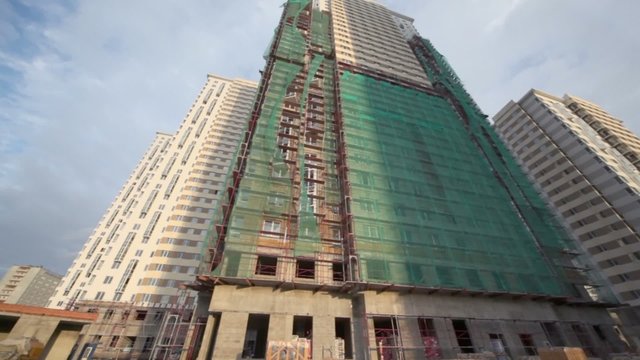 Construction site of tall dwelling houses lit by sunset light