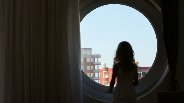 girl closes the curtain on the day of the round window