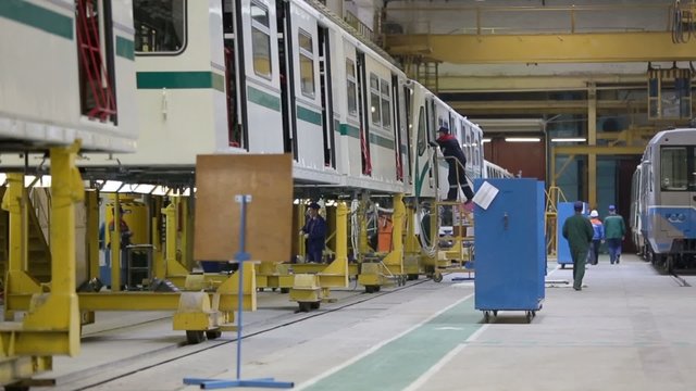 Workers assemble trains at workshop in factory