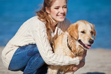 girl are playing with a dog on the beach
