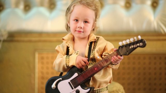 Cute little boy in pop retro costume with guitar toy