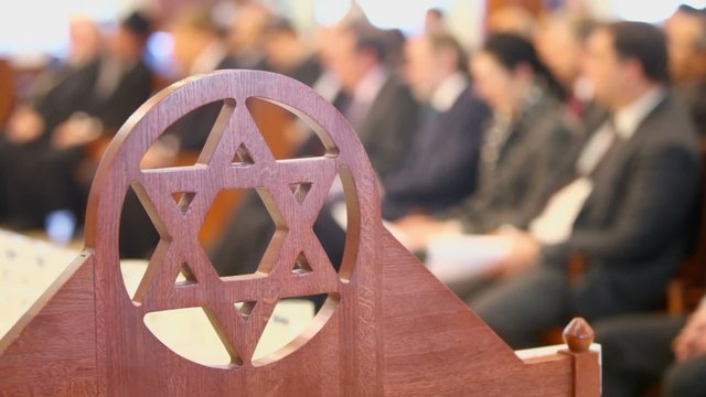 Many sit in synagogue behind wooden merkaba symbol at memorial