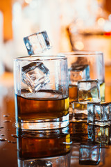 whiskey glass with ice and warm light on black table