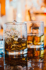 whiskey glass with ice and warm light on black table