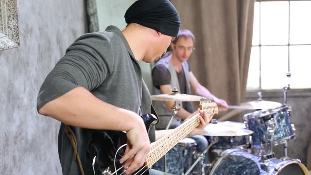 Bass guitarists and drummer play in room powdered with snow