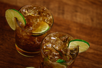 drink concept - cocktail with cola ice cubes and lime