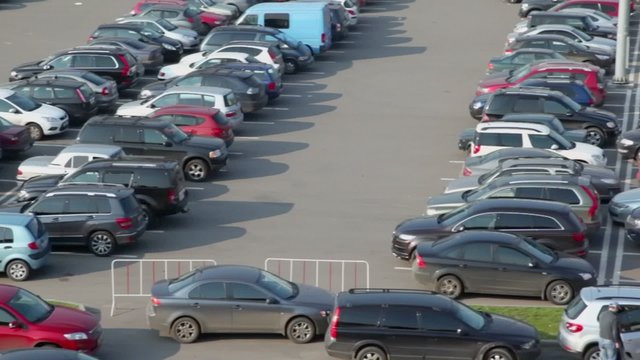 Man opens door in car near parking with lot of vehicles