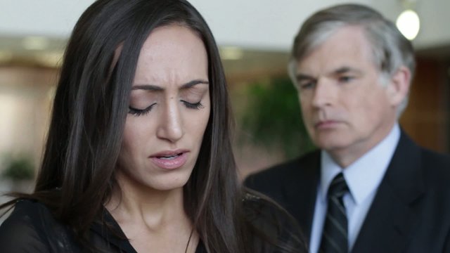 Woman is fired by a harsh male employer in a modern office building.  Woman reacts then leaves, employer watches her go.  Close up with shallow focus.  Could also be used to illustrate different kinds of relationship ending.