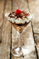 Tasty tiramisu dessert in glass, on wooden background