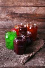 Homemade jars of fruits jam on rustic wooden background