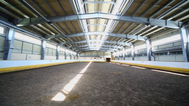 Indoor horse riding hangar with sandy covering