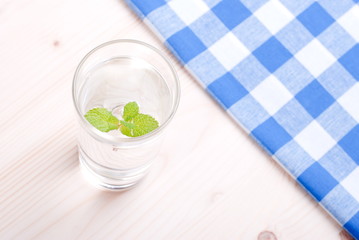 glass of clean water with mint on a table covered with a checker