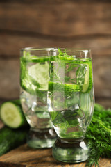 Glasses with fresh organic cucumber water on wooden table