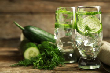 Glasses with fresh organic cucumber water on wooden table