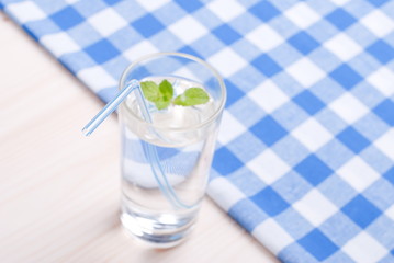 glass of clean water with mint on a table covered with a checker