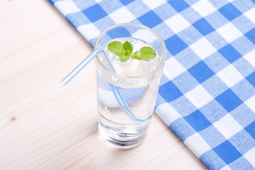 glass of clean water with mint on a table covered with a checker
