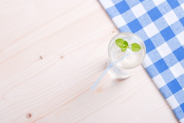 glass of clean water with mint on a table covered with a checker