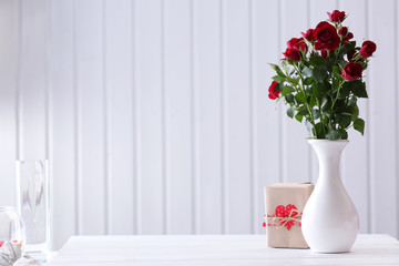 Bouquet of red roses in vase with present box