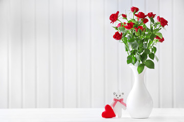 Bouquet of red roses in vase on wooden planks background