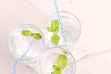 glass of clean water with mint on a table covered with a checker