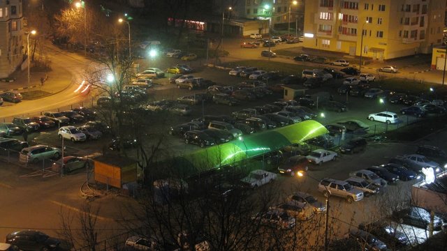 Night city: cars parked in parking lot, zoom. Timelapse