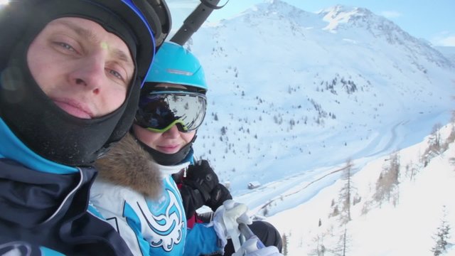 Three skiers in helmets ride on cableway at mountains