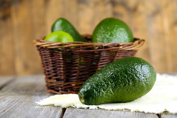 Avocado with limes in basket on wooden background