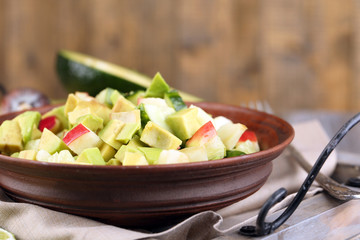 Salad with apple and avocado in bowl on tray on table close up