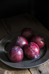 Fresh plums in natural light setting with moody vintage retro st