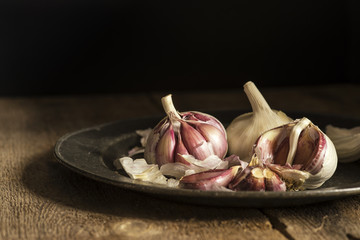 Fresh garlic cloves in moody natural lighting set up with vintag