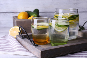 Fresh water with lemon and cucumber in glassware in wooden