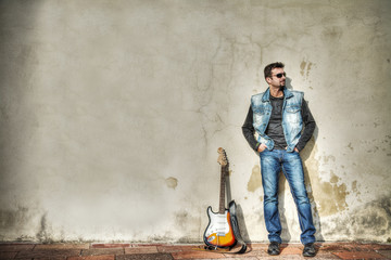 man and guitar leaning on the wall