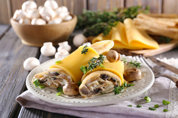 Pancakes with creamy mushrooms in plate on wooden table,