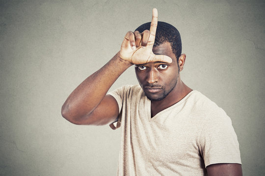 man showing loser sign on forehead looking at you