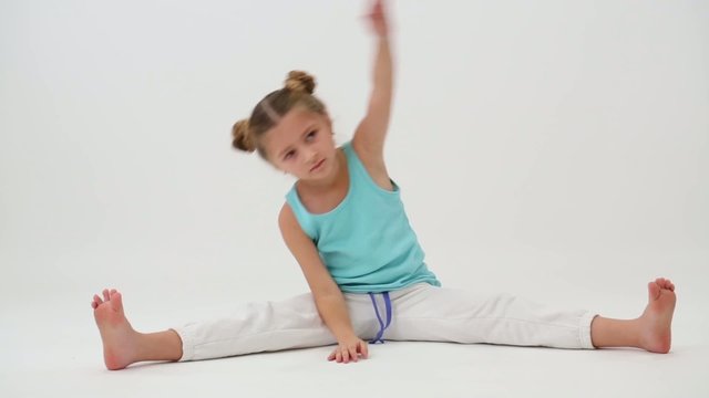 Little girl makes gymnastic exercise sitting on splits
