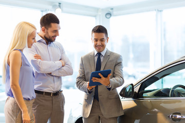 happy couple with car dealer in auto show or salon