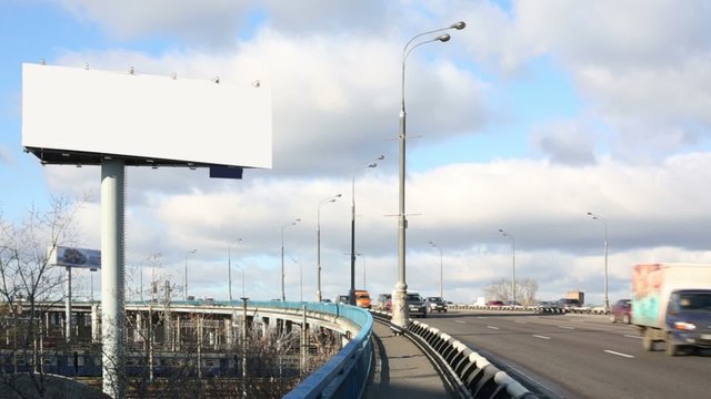 Route with moving cars and big blank billboard at sunny day
