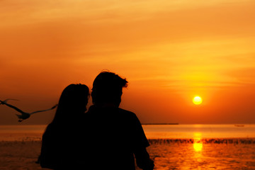 Fototapeta na wymiar Silhouette couple at the seacoast in twilight sunset background