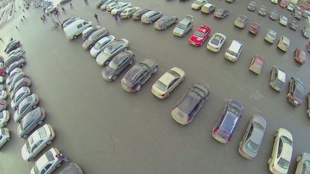 People walk by parking with lot of cars at winter day in Moscow