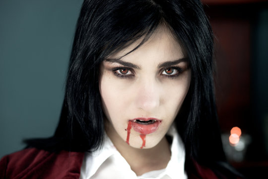 Beautiful vampire with blood looking camera
