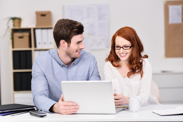 junge leute sitzen am schreibtisch und schauen auf laptop