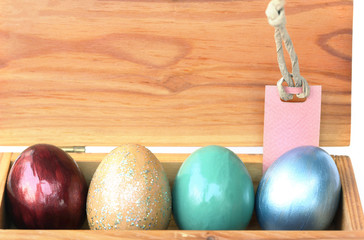 Colorful easter egg in wood box with paper tag.