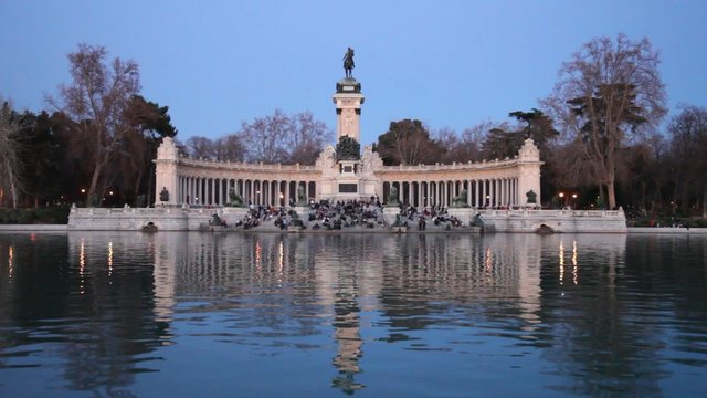 MADRID - MAR 11: People sitting on the pond shore in front of monument to Alphonso XII, on Mar 11, 2012 in Madrid, Spain.