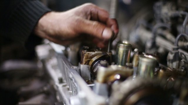 hands unscrews screw by screwdriver of gasoline car motor