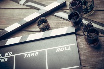 Film. Movie clapper and film reel on a wooden background