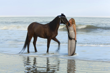 dreamy shot of woman with horse in the ocean