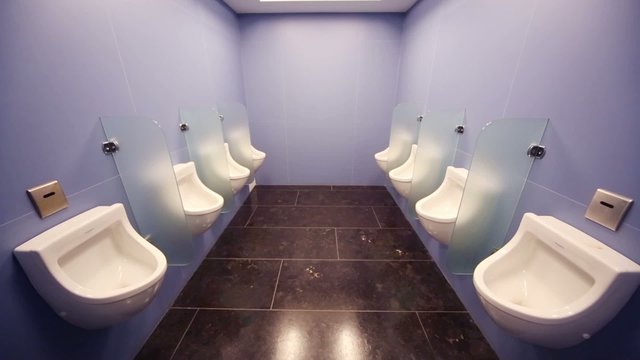 Interior of public men room with white urinals and tiles