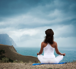Fototapeta na wymiar Woman Practicing Yoga at Stormy Sea