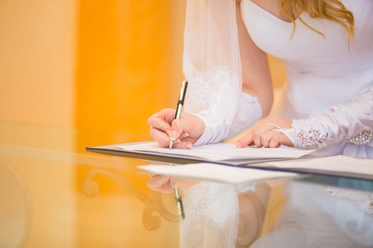 bride putting signature into wedding certificate